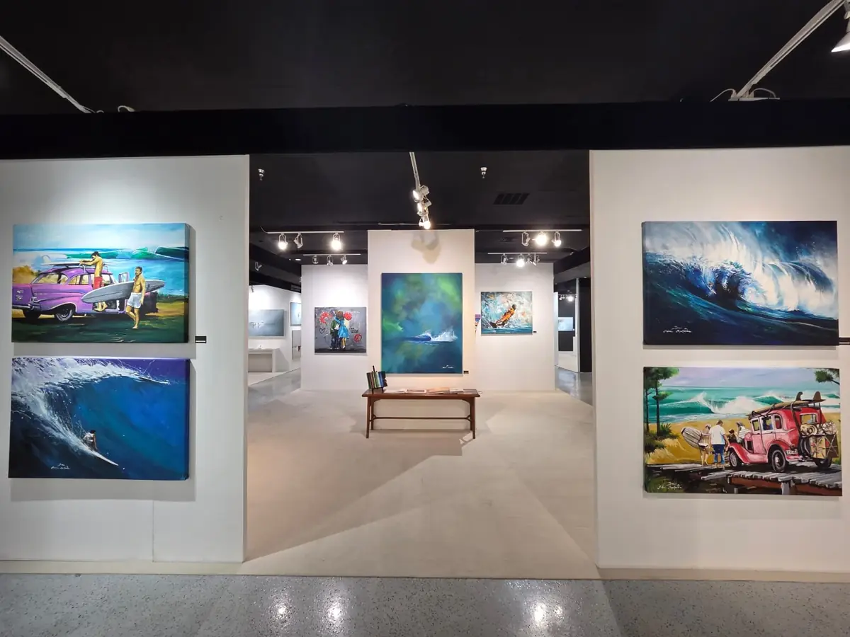 Vue d’une galerie présentant des peintures de vagues et de culture surf