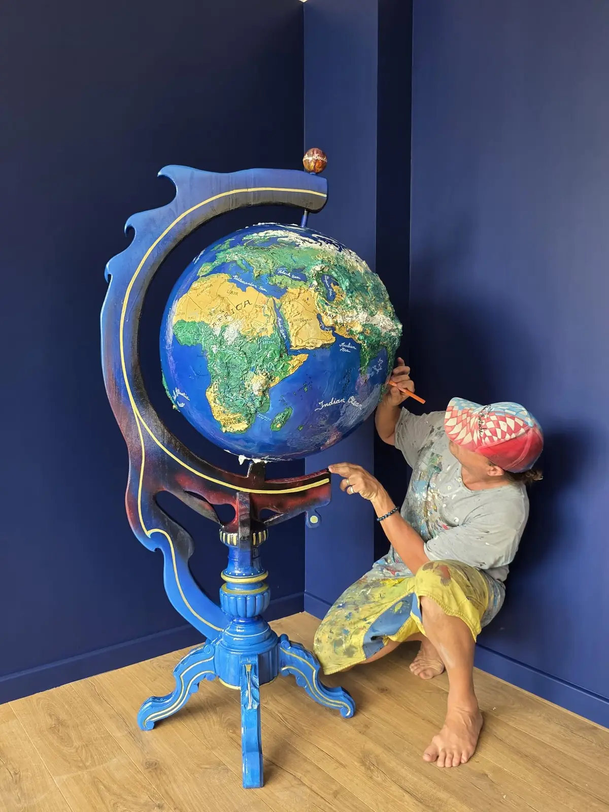 Rémi Bertoche peignant à la main un globe monumental dans son atelier